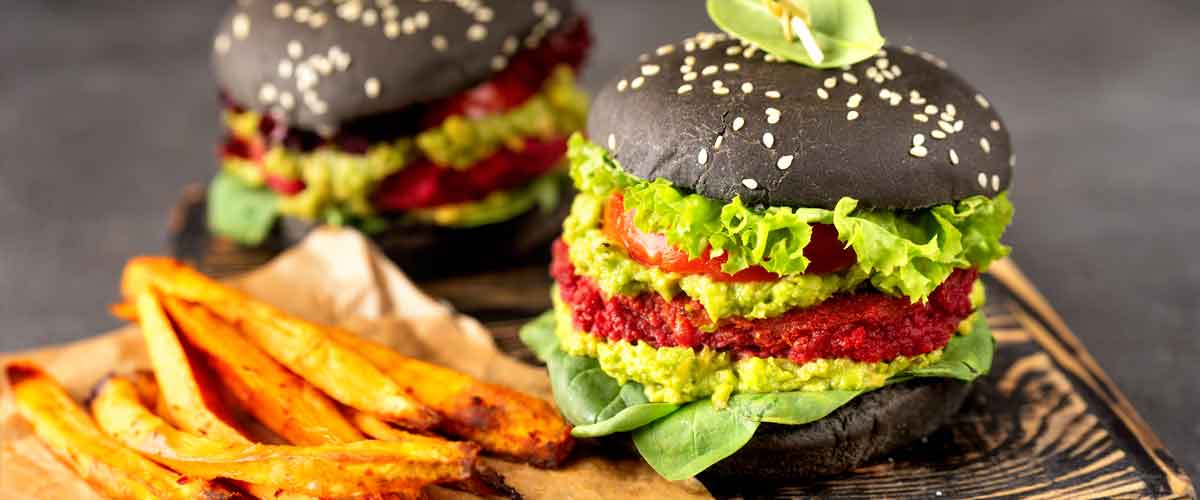 Da möchte jeder gleich reinbeißen: Veganer Black-Burger mit Avocado, Paprika-Tomaten-Tatar und Süßkartoffel Pommes.