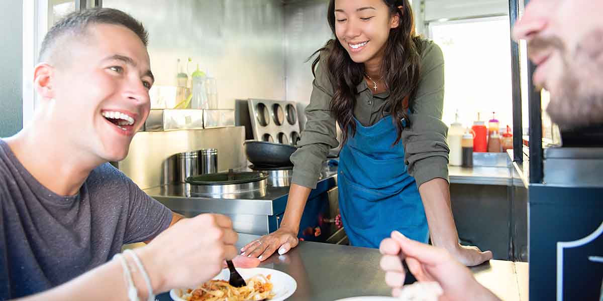 Zwei Personen genießen am Foodtruck ihr essen